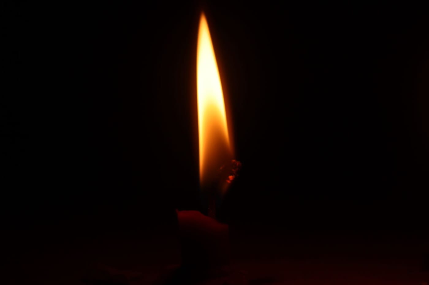 A single candle flame in a dark room